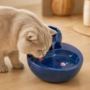 Luma Flow blauwe keramische kattenfontein met kat die uit de lage drinkschaal drinkt